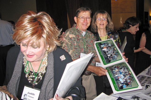 Judith Foman, Tom Tiesner and his wife Kathleen look at class photos.